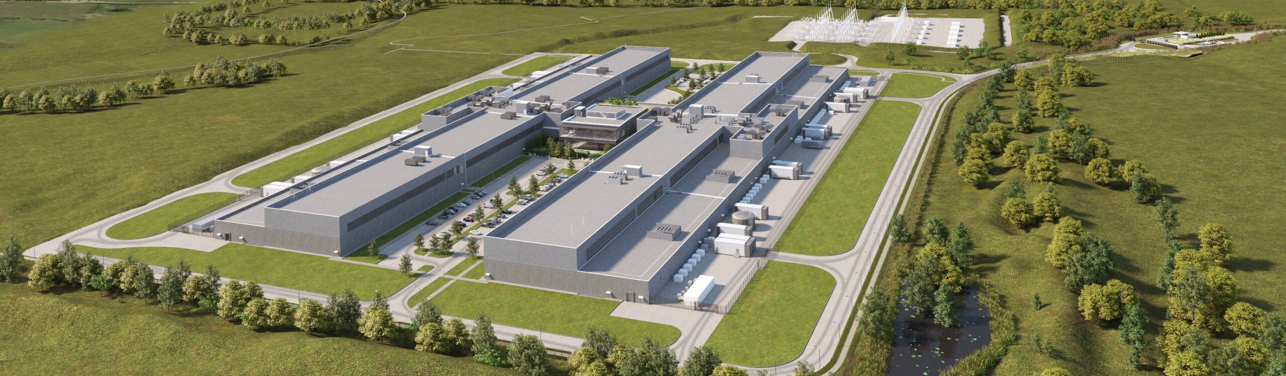 Aerial view of a large, modern data center complex with multiple long rectangular buildings surrounded by grass, trees, and access roads, set in a rural area.