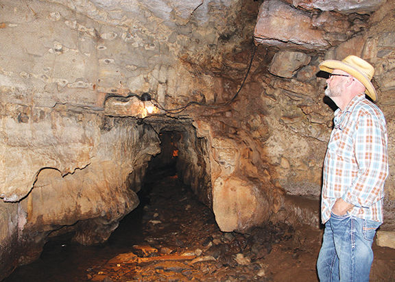 A man in a cowboy hat looking at the inside of Bell Witch Cave.