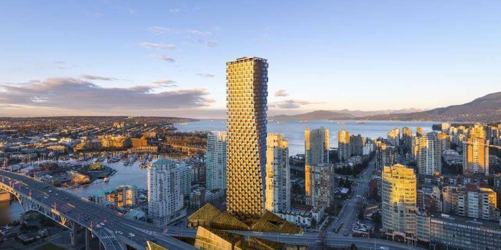 A modern cityscape at sunset shows a tall, twisting skyscraper surrounded by other buildings, with water, boats, bridges, and distant mountains in the background.
