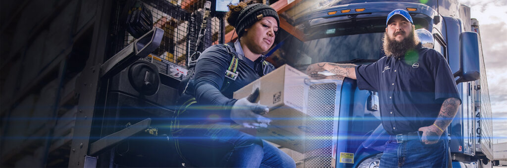A delivery worker places a package onto a forklift, while another worker with a beard and cap stands beside a blue semi-truck, both wearing work uniforms and safety gear.
