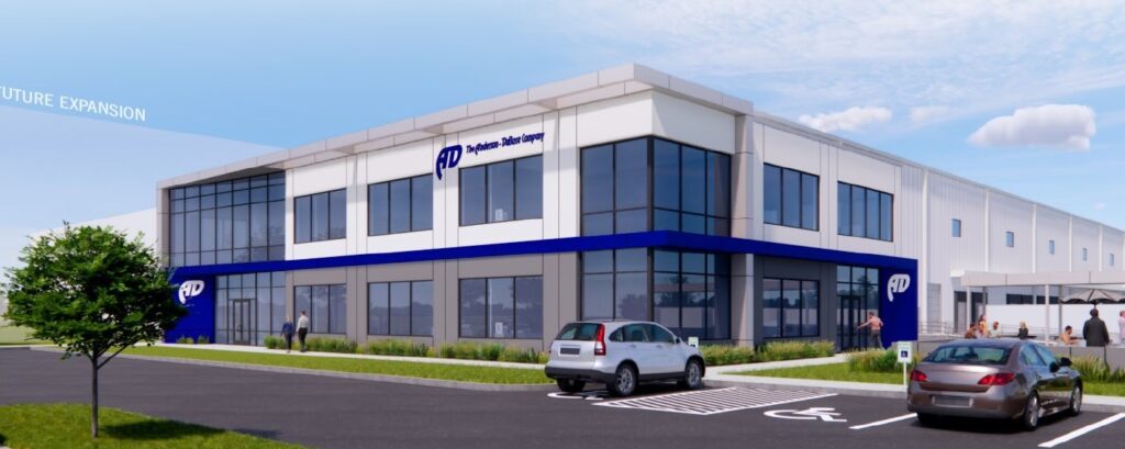 Modern office building with large windows, blue and white exterior, and the "Applied Industrial Technologies" logo. People walk nearby, and cars are parked in front, including one in an accessible parking spot.