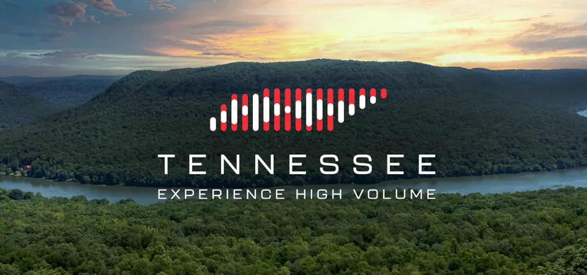 A scenic view of a river winding through lush green hills at sunset, with the words "Tennessee" and "Experience High Volume" overlaid, along with a stylized soundwave graphic above the text.