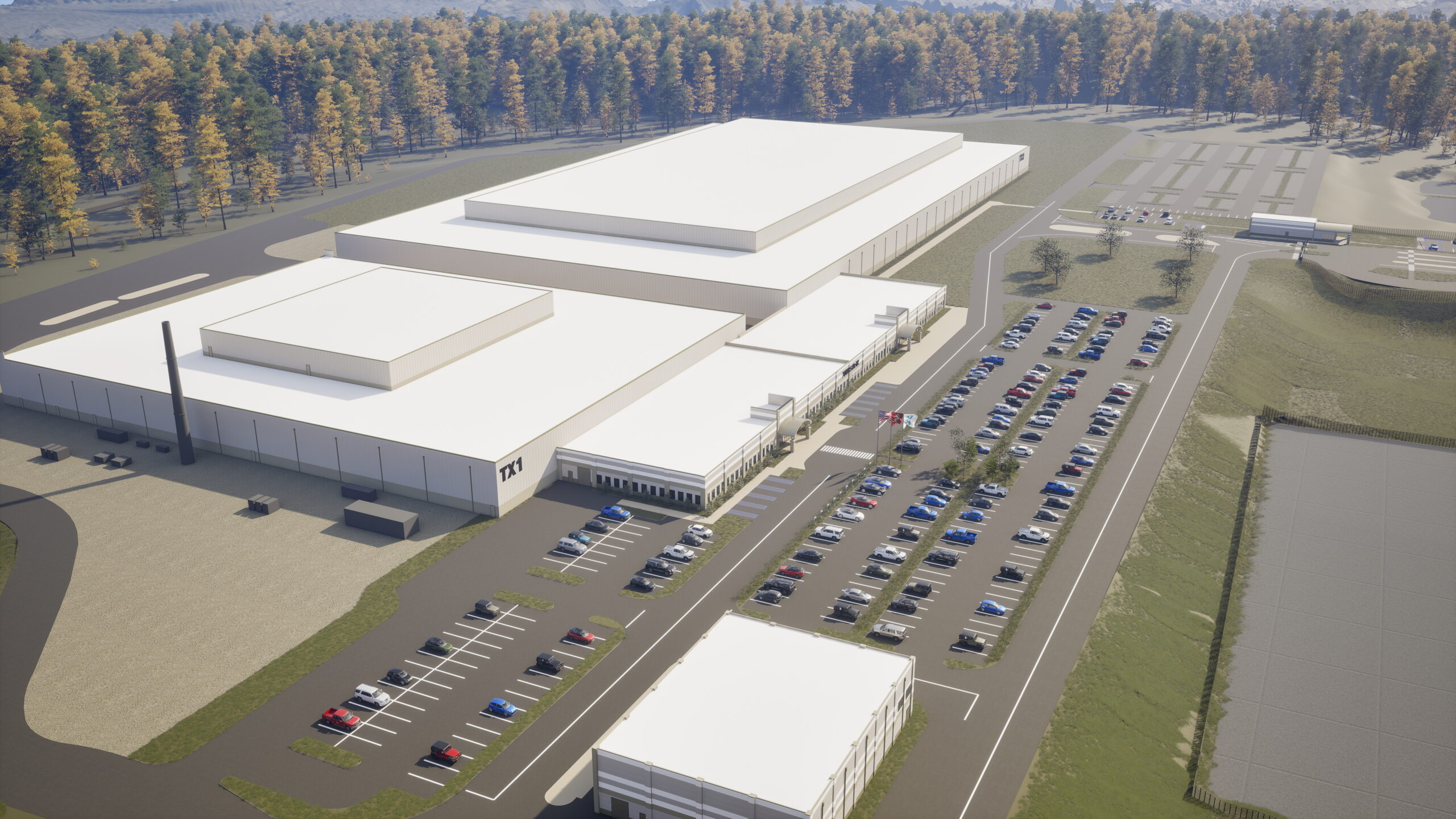 Aerial view of a large white industrial complex with adjacent parking lots full of cars, surrounded by trees and greenery.